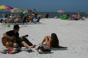 spring breakers on beach playing guitar