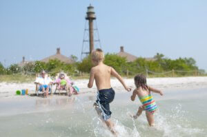 children running toward parents sitting on beach